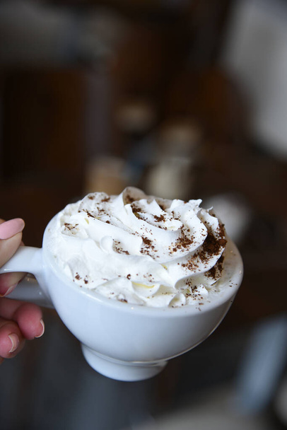 рука держа чашку кофе со взбитыми сливками - Фото, изображение