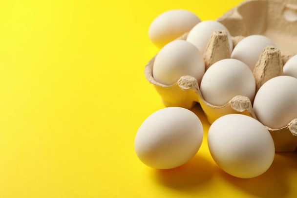 Яєчна коробка зі свіжими яйцями на жовтому фоні
 - Фото, зображення