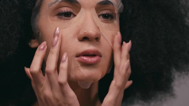 Afrikaans amerikaanse vrouw aanbrengen gezichtsmasker geïsoleerd op grijs - Video