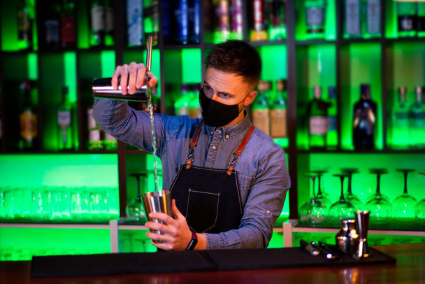 Mladý chlap pracuje jako barman při přípravě koktejlů v hospodě - Fotografie, Obrázek