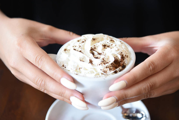 vrouwelijke handen houden kopje koffie met slagroom - Foto, afbeelding