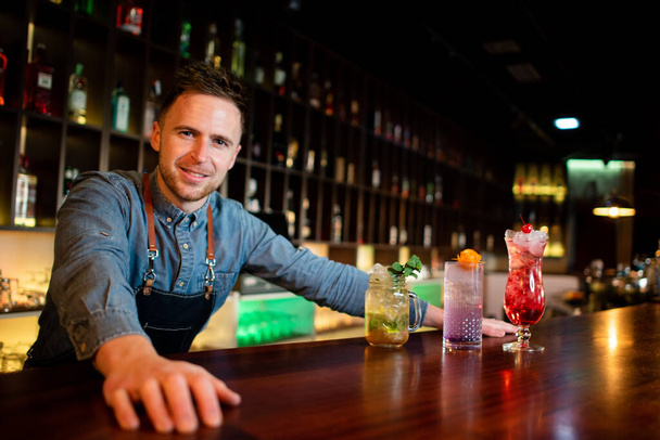 Młody facet pracuje jako barman podczas przygotowywania koktajli w pubie - Zdjęcie, obraz