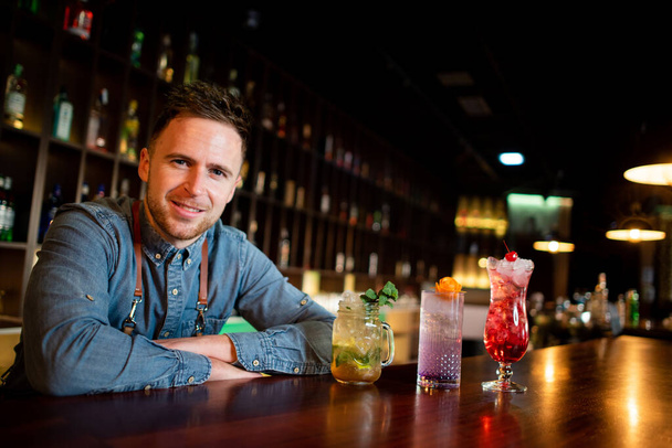 Jongeman een werken als een barman tijdens het bereiden van cocktails in een pub - Foto, afbeelding