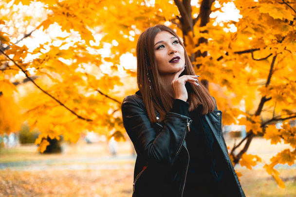 Cute woman in black clothes on a background of maple autumn leaves - Fotó, kép