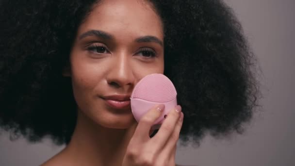 donna afroamericana sorridente utilizzando detergente al silicio isolato su grigio - Filmati, video