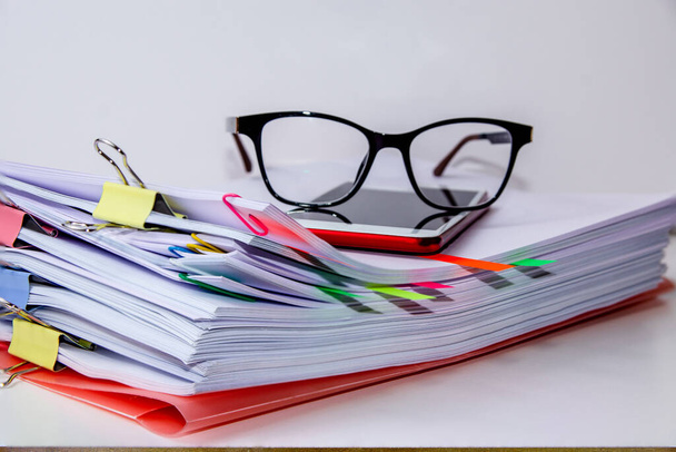 Close-up of glasses and a smartphone on a pile of folios. Information overload concept - Φωτογραφία, εικόνα