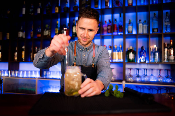 Giovane ragazzo un lavoro come barista durante la preparazione di cocktail in un pub - Foto, immagini