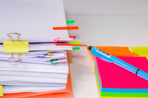 Nahaufnahme eines Papierstapels mit farbigen Post-its und einem Stift. InformationsüberlastungskonzeptGroßaufnahme eines Papierstapels mit farbigen Papieren und einem Stift. Konzept der Informationsüberlastung - Foto, Bild