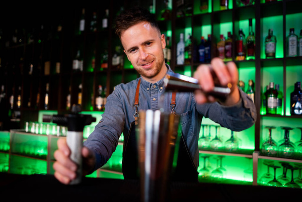 Nuori kaveri työskentelee baarimikko valmistellessaan cocktaileja pubissa - Valokuva, kuva