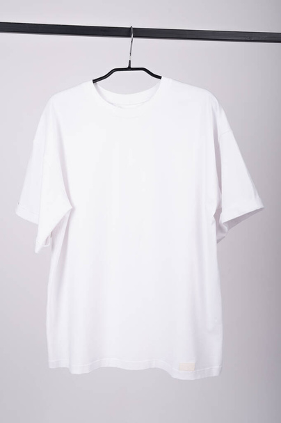 Camiseta blanca cuelga de una percha - Foto, imagen