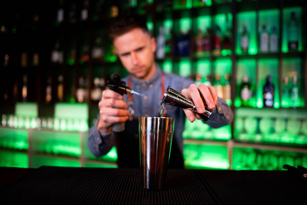 Giovane ragazzo che lavora come barista mentre prepara cocktail in un pub - Foto, immagini