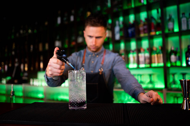 Mladý muž pracuje jako barman, zatímco připravuje koktejly v hospodě - Fotografie, Obrázek