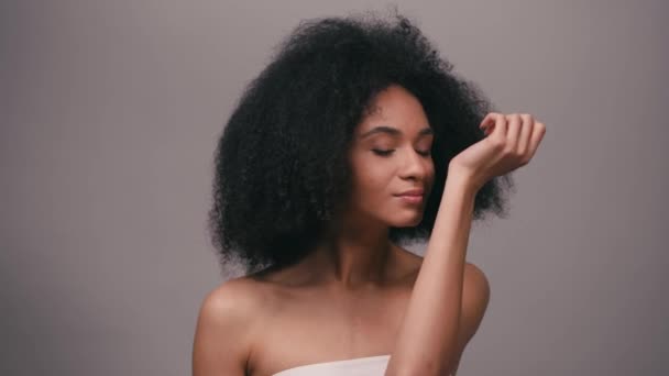 νεαρή Αφροαμερικανή που απολαμβάνει μυρωδιά αρώματος απομονωμένη στο γκρι - Πλάνα, βίντεο