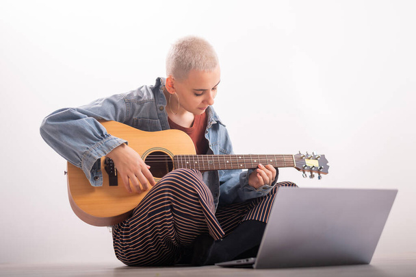 Young hipster woman watching guitar tutorials on laptop. Distance learning music - Φωτογραφία, εικόνα