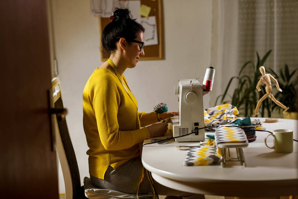 Γυναίκα που ράβει μια ραπτομηχανή στο σπίτι της. Εργασίες μοδίστρας γυναικών στη ραπτομηχανή - Φωτογραφία, εικόνα