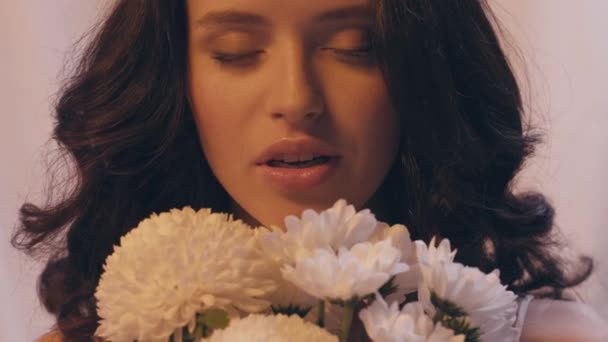 happy woman with wavy hair smelling bouquet of white flowers - Footage, Video