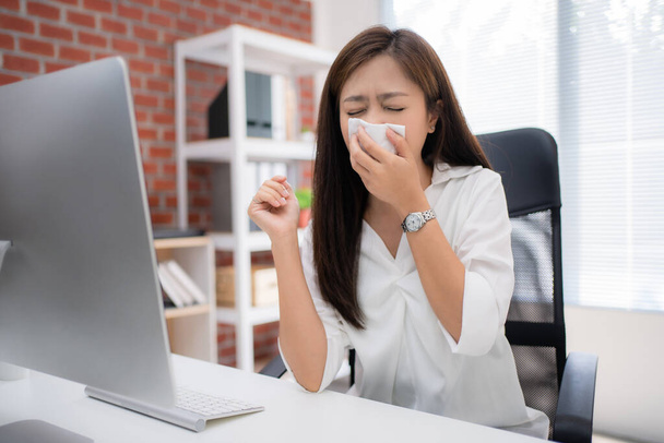 Mujer asiática estornuda. Se cubrió la boca con un pañuelo en el escritorio de casa.. - Foto, imagen