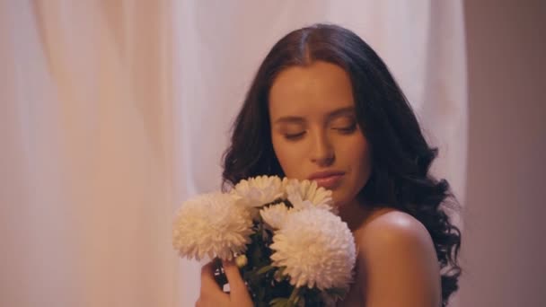 slow motion of woman with wavy hair holding bouquet of white flowers on grey - Footage, Video