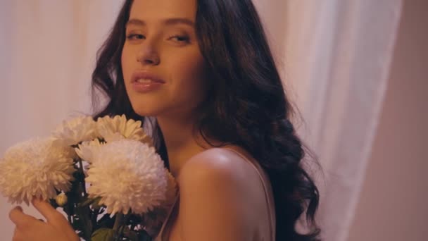 slow motion of young woman holding bouquet of white flowers on grey - Footage, Video