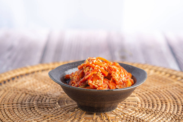 Side view of traditional Korean dishes (Kimchi) in a bowl on rattan handmade pacemat. Space for text. Concept of Korean foods. - Photo, Image