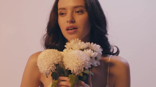 young woman smelling bouquet of white flowers and smiling isolated on grey - Footage, Video