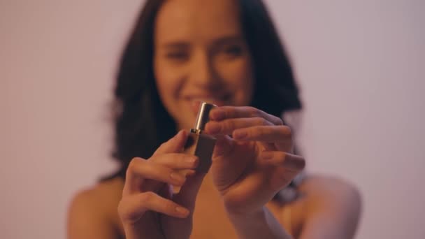 mujer borrosa torciendo y abriendo lápiz labial aislado en gris - Imágenes, Vídeo