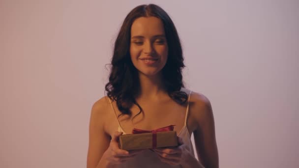 стойка фокус счастливой женщины представляя подарочную коробку изолированы на серый - Кадры, видео