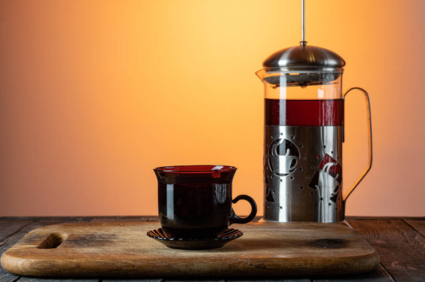 Glass flask with tea. Tea mug and teapot. Tea on the kitchen board. Teapot and mug. - Фото, зображення