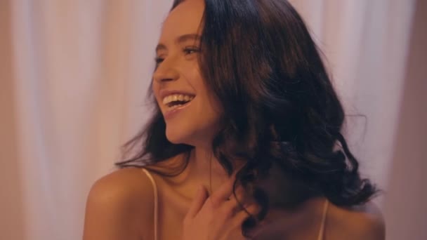 αργή κίνηση της ευτυχισμένης μελαχρινής γυναίκας με κυματιστά μαλλιά γελώντας στα λευκά - Πλάνα, βίντεο