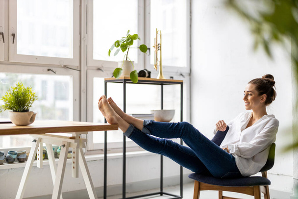 Young woman relaxing in office with her bare feet on desk  - Foto, Bild