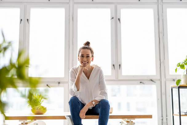 Portrait of a smiling creative woman in a modern loft space - Foto, afbeelding