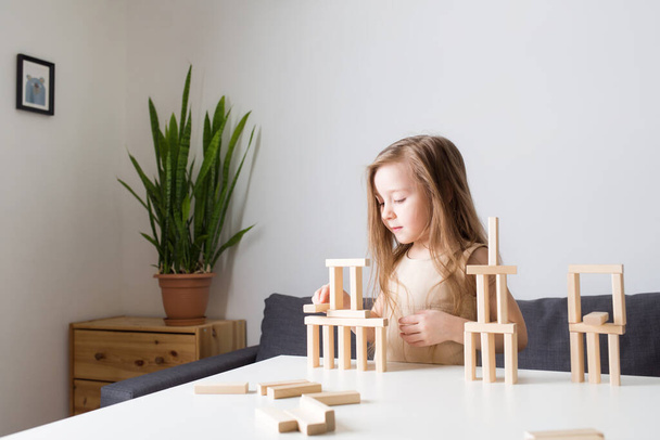 kids playing with wooden jenga constructor. girl builds towers from toy rectangular blocks. concept of developing fine motor skills, games. Leisure activities for children at home. - Foto, immagini