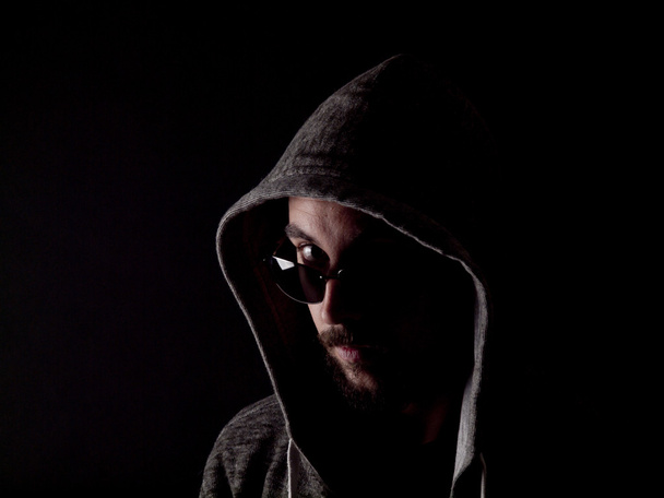 Low key image of a bearded man with a hoody and sunglasses - Zdjęcie, obraz