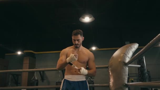 γενειοφόρος ισπανόφωνος πυγμάχος τυλίγει τα χέρια με ταινία πυγμαχίας και άσκηση στο γυμναστήριο - Πλάνα, βίντεο