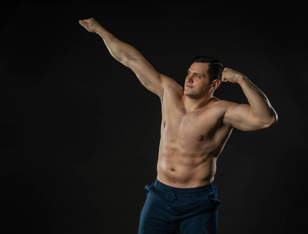 Male biceps shows bare torso arm stretched up Young male male adult, modern happy. Studio formal, successful smile background black bodybuilder - Foto, Imagem