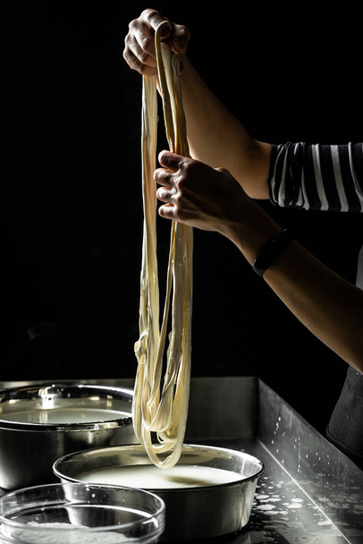 Cheesemaker toont de procedure om kaas te maken van de biologische melk. De zelfgemaakte kaasmaker produceert caciocavallo. Pasta filata, Traditionele Italiaanse mozzarella. - Foto, afbeelding