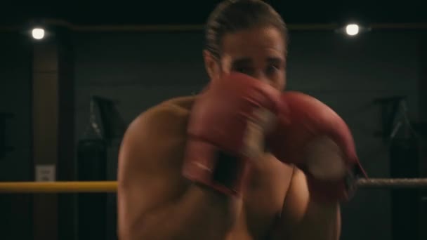 Spaanse shirtloze man in bokshandschoenen die op de boksring traint  - Video