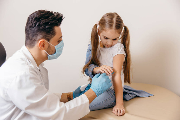 Un medico di nazionalità araba o turca ha vaccinato la bambina contro il coronavirus. Le ragazze sono ferite.. - Foto, immagini