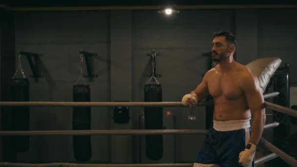 Boxer esausto con nastro da boxe su bottiglia per mani con acqua  - Filmati, video