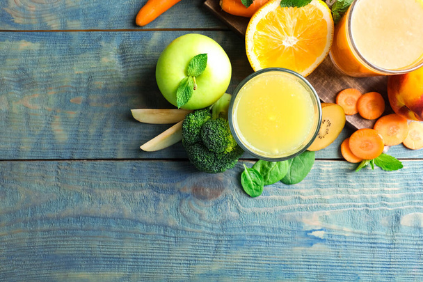 Glasses of delicious juices and fresh ingredients on blue wooden table, flat lay. Space for text - Photo, image