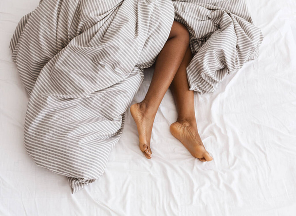 Тонкие, идеальные и красивые скрещенные женские ноги на кровати в отпуске и отпуске - Фото, изображение
