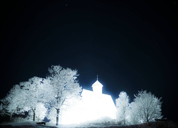 Middeleeuwse kerk van licht, overbelichte nachtfotografie van een christelijke kerk op een heuvel. Hoge kwaliteit foto - Foto, afbeelding