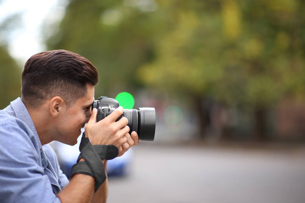 Photographer taking picture with professional camera on city street - Photo, Image