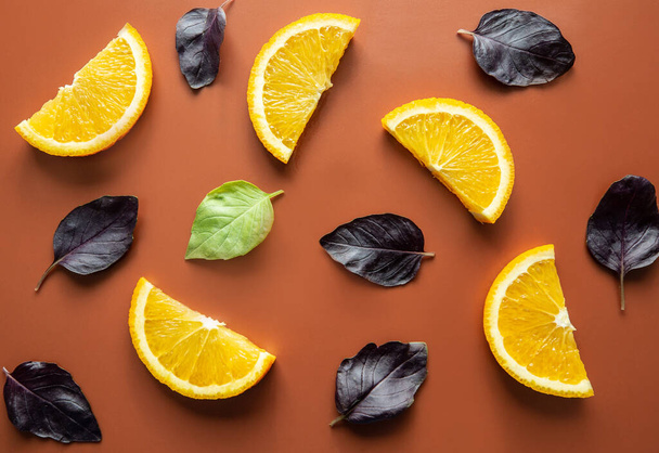 slices of orange and basil leaves, close up, flat lay, brown background - Photo, Image