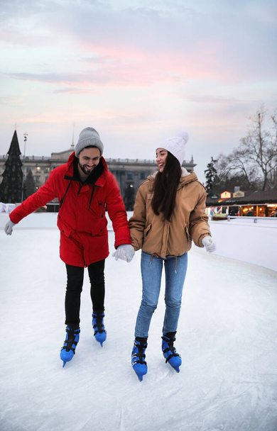 Happy young couple skating at outdoor ice rink - Foto, Bild