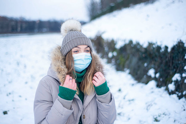  a girl in a jacket and a respirator, woman in a mask in winter, protection against coronavirus, health care, self-isolation - Photo, Image