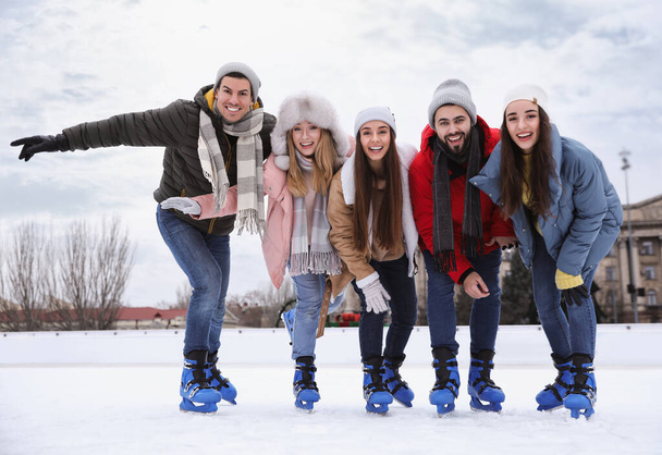 Happy friends at ice skating rink outdoors - Foto, Imagen