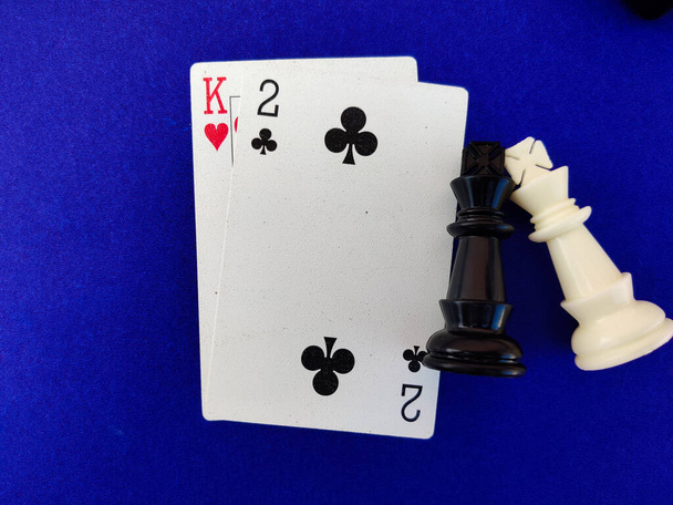 Сердце короля игральные карты с белым черным шахматным королем изолированы на синем фоне. - Фото, изображение