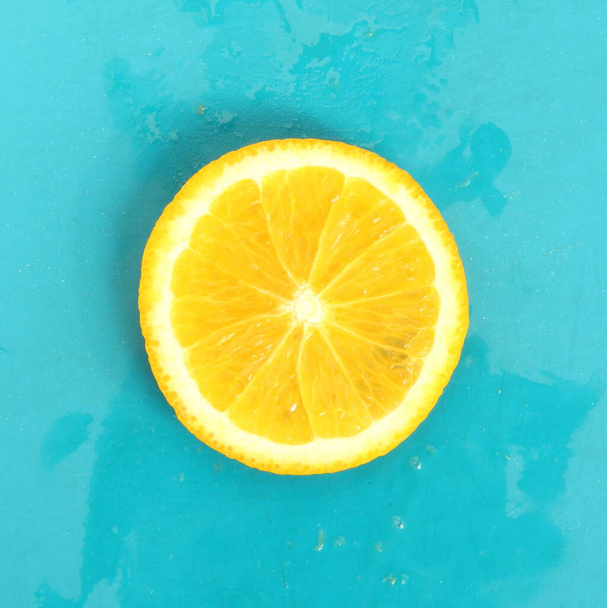 Close up of round lemon slice on blue background, fresh summer mood - Фото, изображение