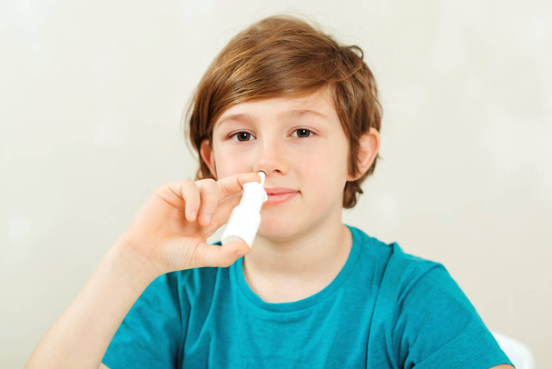 Nemocný školák s tekoucím nosem za použití nosního spreje. Alergie na nos. Dítě s nemocnou nemocí období léčby. Alergické dítě, chřipková sezóna. Chlapec má virus, teče mu z nosu a bolí ho hlava. Školák s tekoucím nosem - Fotografie, Obrázek